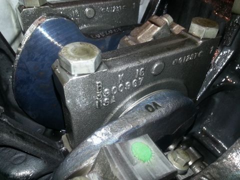 1994 Ford Bronco - Close-up view of a cast iron engine component with stamped markings including 'B 6000967 K 16 USA' and '6012876'. A hexagonal bolt is visib…