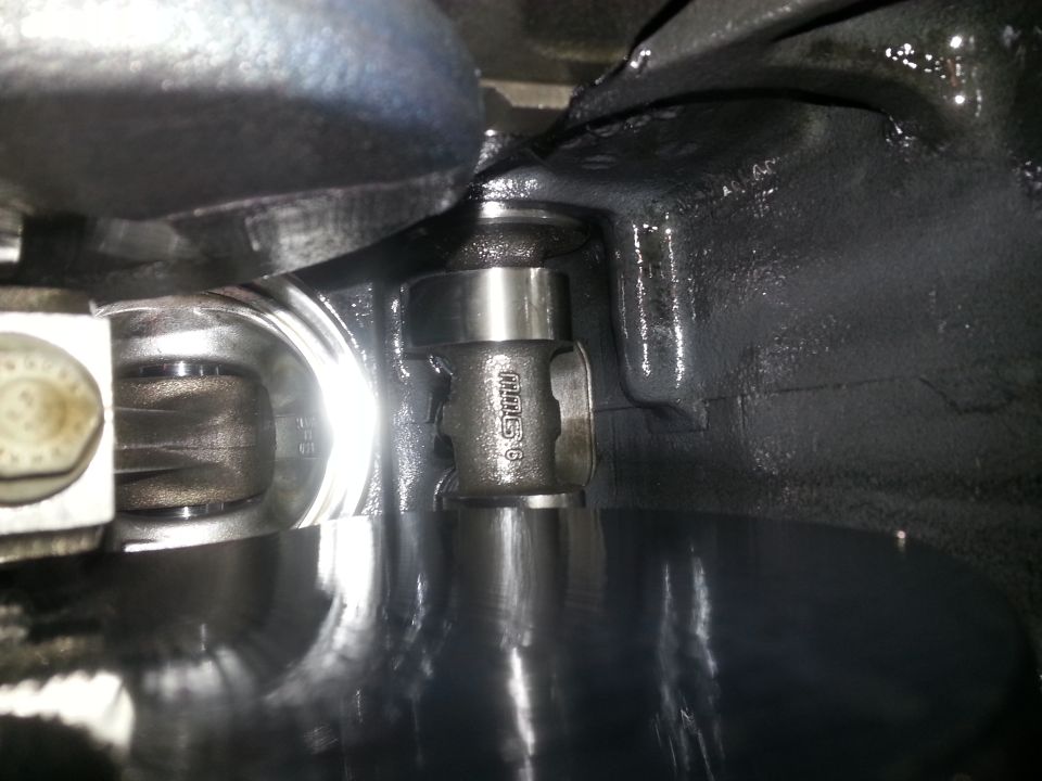 Internal engine components showing crankshaft and connecting rod with oil.