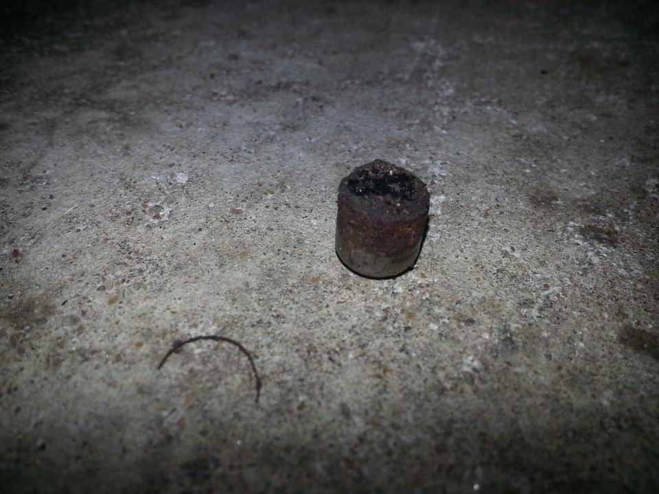 Cylindrical object with burnt top on concrete surface.