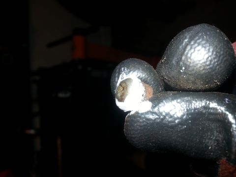 1994 Ford Bronco - A close-up shot shows a gloved hand holding a bolt with white sealant or grease around it. The bolt appears to be part of some mechanical c…