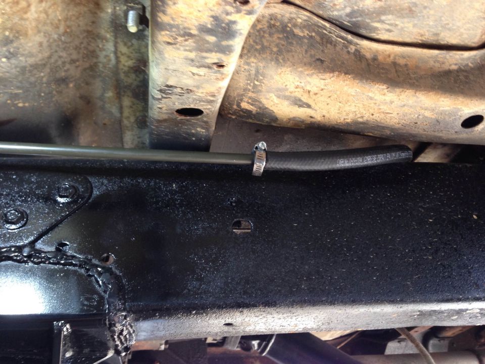Close-up of a black hose and silver line attached to a black frame with a hose clamp.
