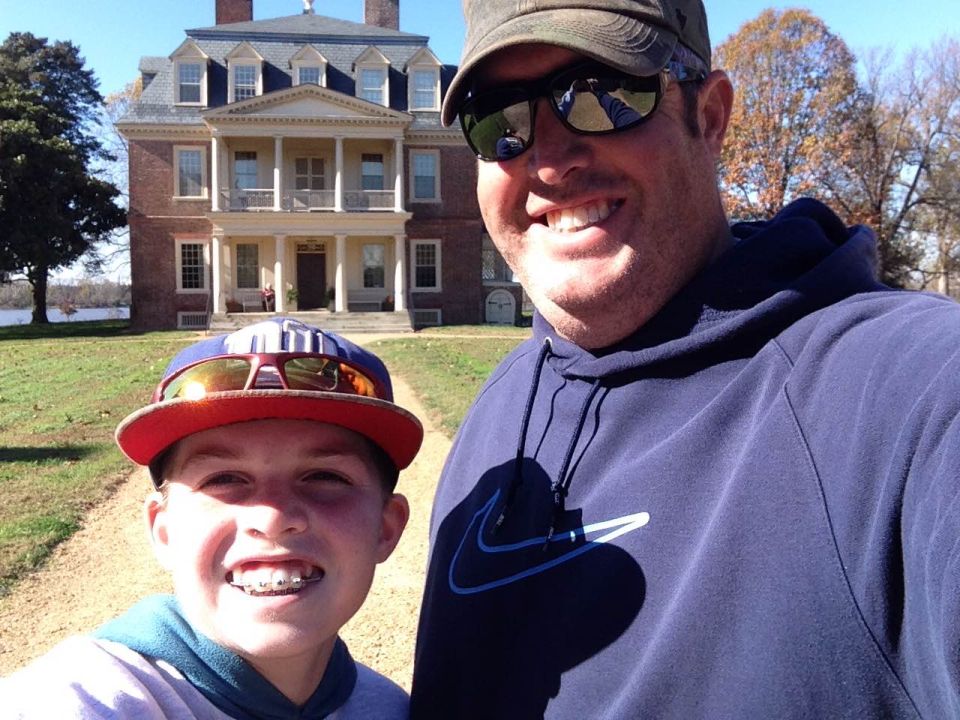 A man and a boy take a selfie in front of a historic brick building.