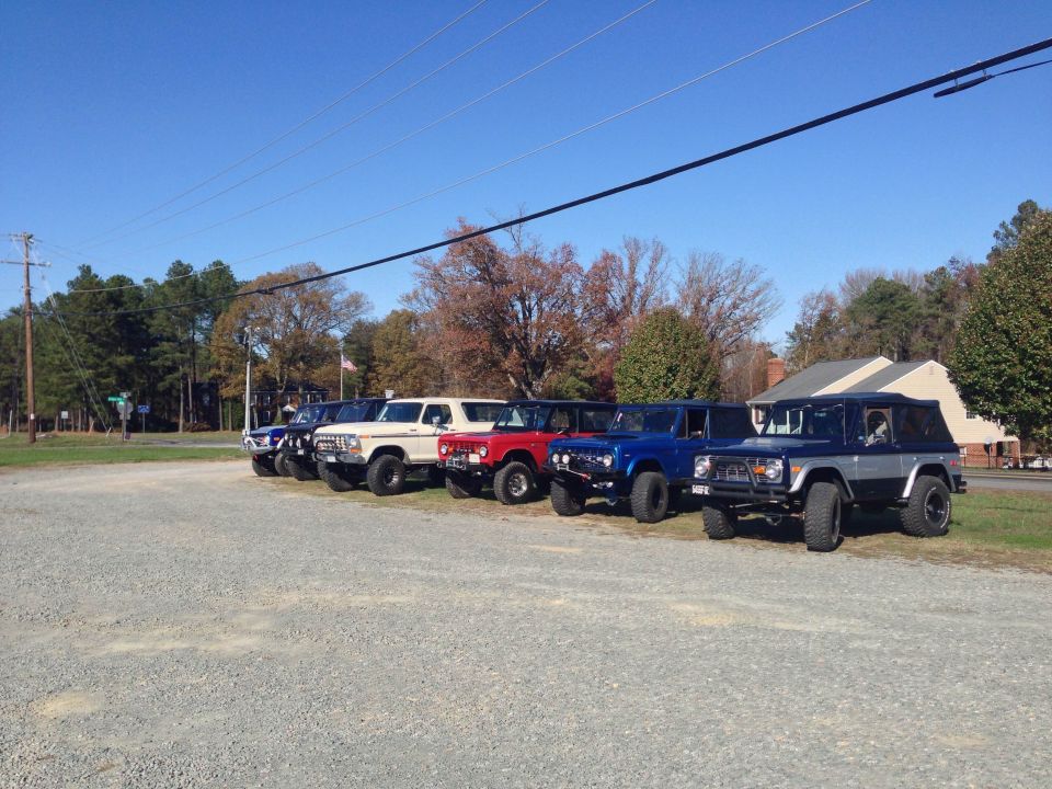 Line of classic Ford Broncos parked in a gravel lot.