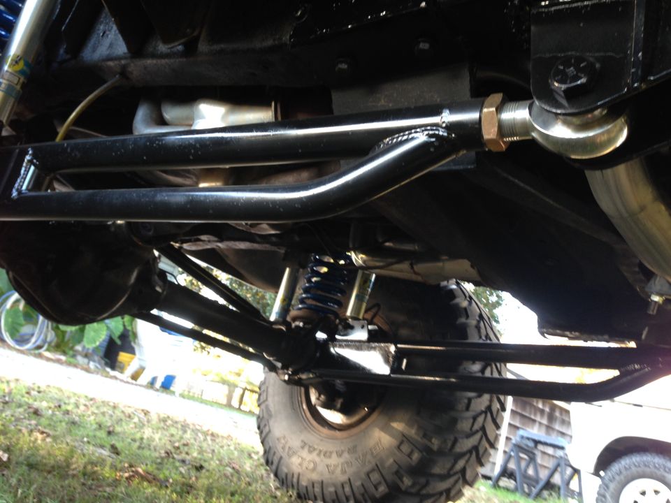 Underside of a modified vehicle showing suspension, large tire, and shocks.