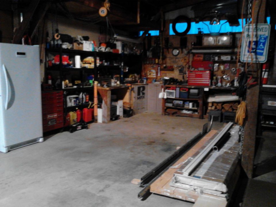 A cluttered garage with tools, shelves, and lumber.