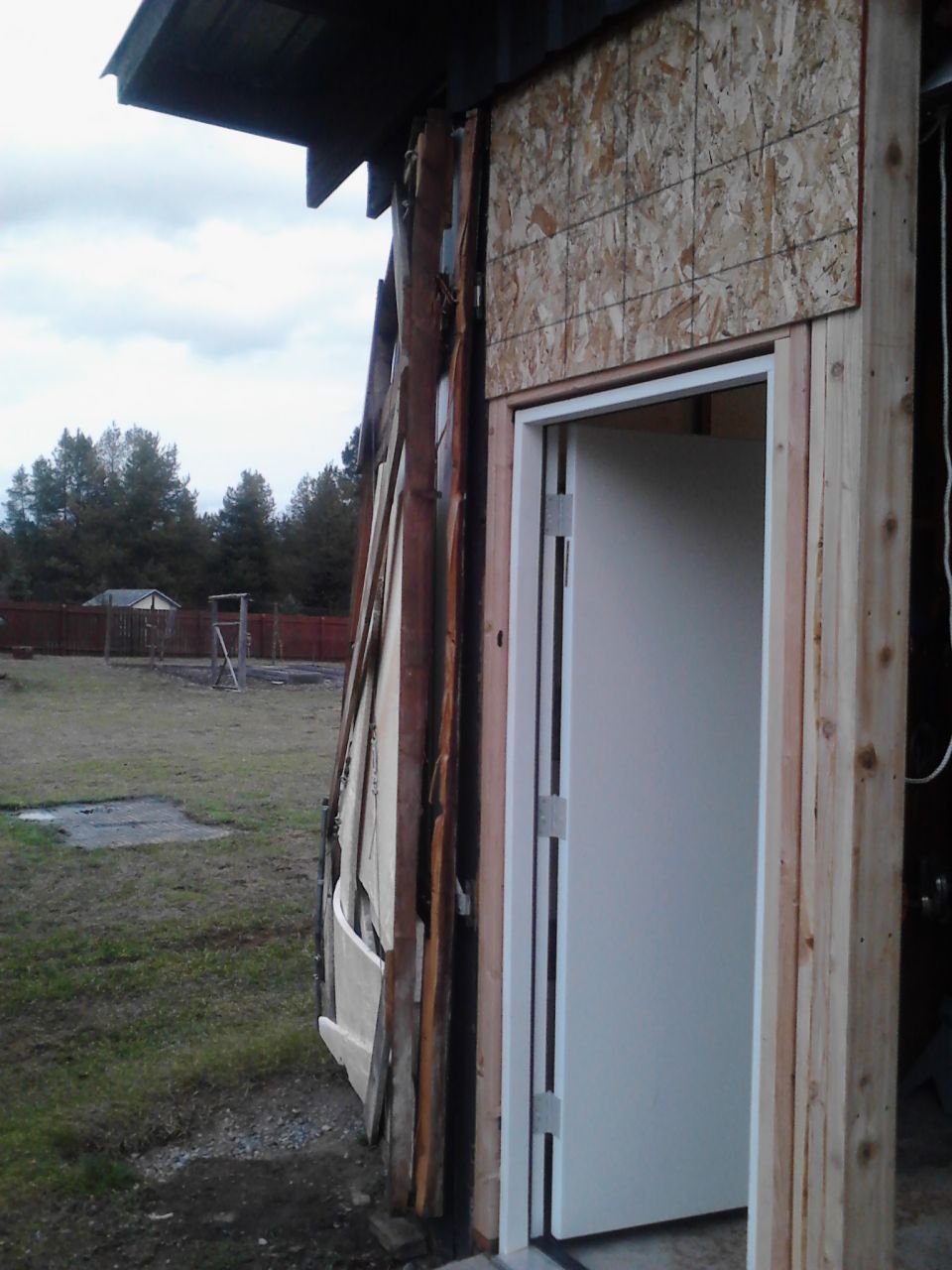 Exterior of a building under construction with a white door and exposed framing.