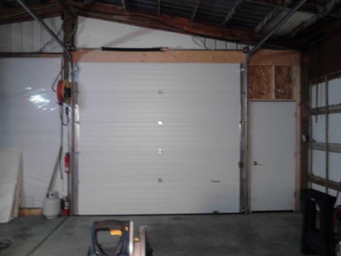 1989 Ford Bronco - This is an interior scene of a garage or workshop with a large white overhead door, a white side door, and various equipment including a pr…