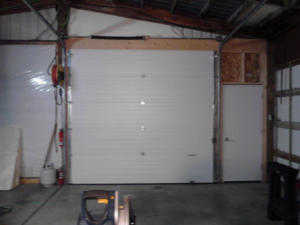 Interior of a garage with a large white garage door and a smaller white door.