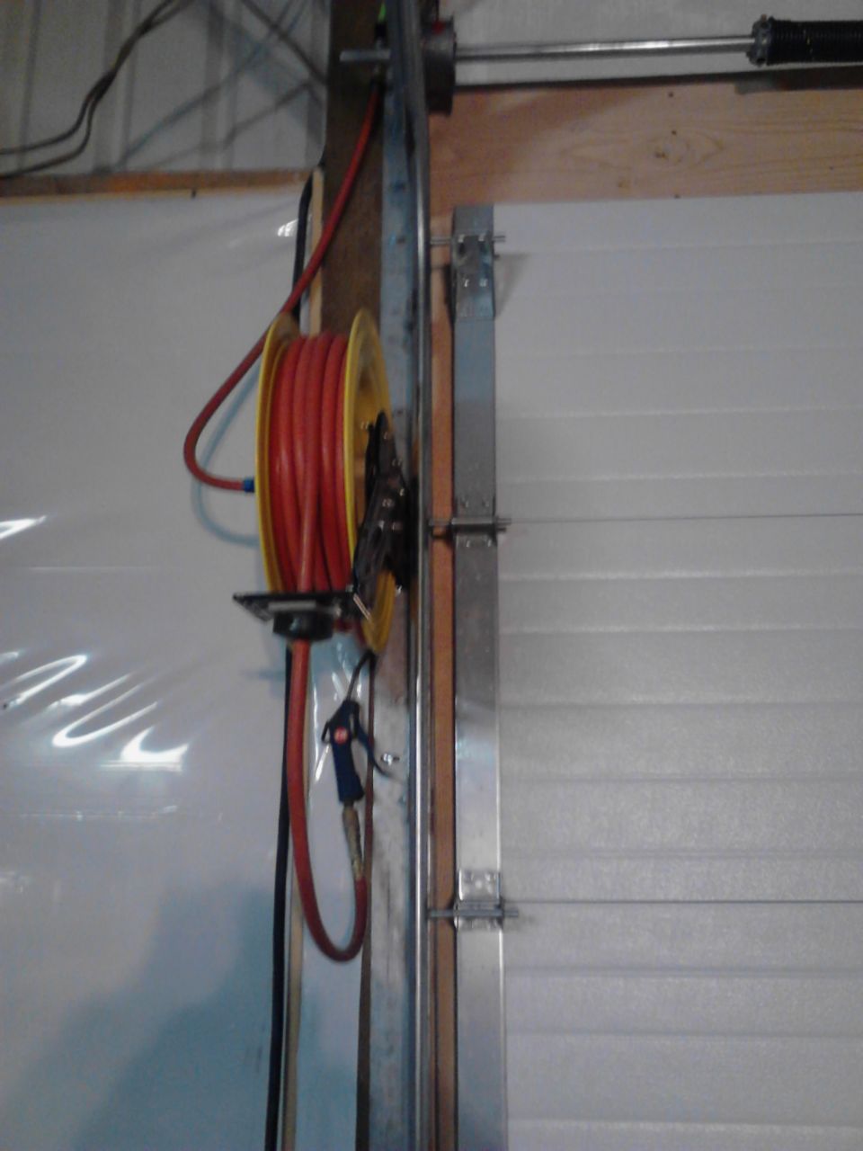 Red air hose on a yellow reel mounted on a wall.