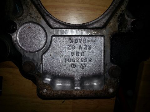 1994 Ford Bronco - A close-up shot of a metal part with embossed text that reads "VW O 3912601 USA REV 02 A1214 BACK". The part appears to be a component of a…