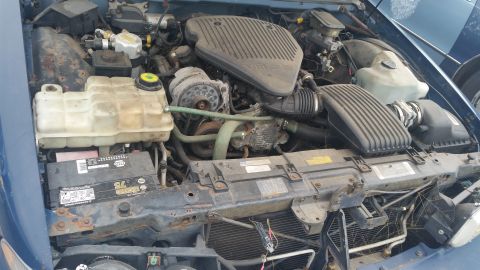 1991 Ford LTD Crown Victoria - Photograph of a vehicle engine bay with intake, battery and fluid reservoirs, not a technical document.
