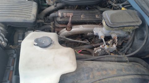 1991 Ford LTD Crown Victoria - Photograph of an engine bay with washer reservoir and valve cover, not a technical document.