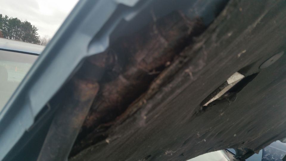 Rusted, corroded body seam under a vehicle hood edge