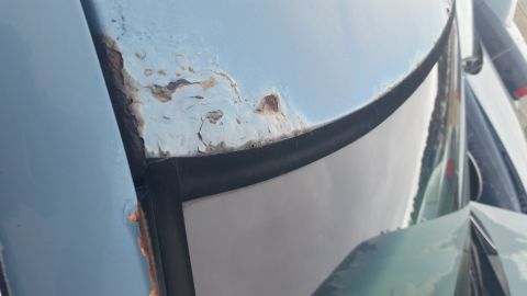 1991 Ford LTD Crown Victoria - Photograph of heavy rust and peeling paint on a car roof edge, not a technical document.