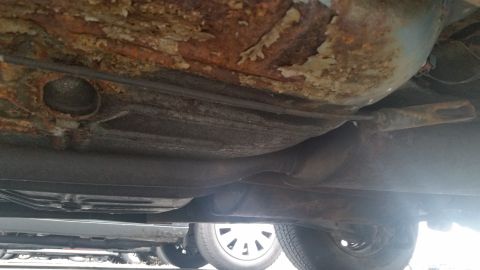 1991 Ford LTD Crown Victoria - Photograph of a corroded vehicle undercarriage with exhaust pipe, not a technical document.