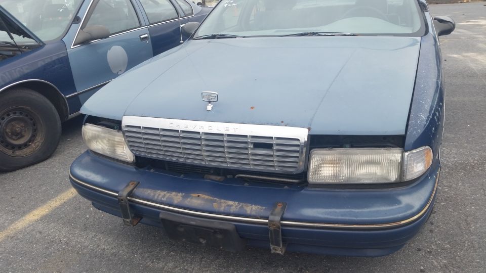 Front view of a blue Chevrolet Caprice with chrome grille in a parking lot