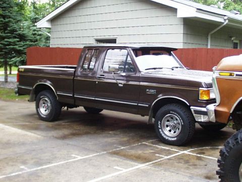 1989 Ford F-150 - A brown Ford F-150 pickup truck is parked next to another vehicle.
