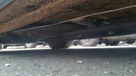 1991 Ford LTD Crown Victoria - Photograph taken under a vehicle showing the chassis and wheels, not a technical document.