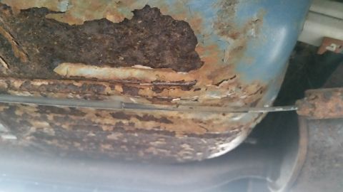 1991 Ford LTD Crown Victoria - Photograph of a heavily rusted lower body panel, not a technical document.