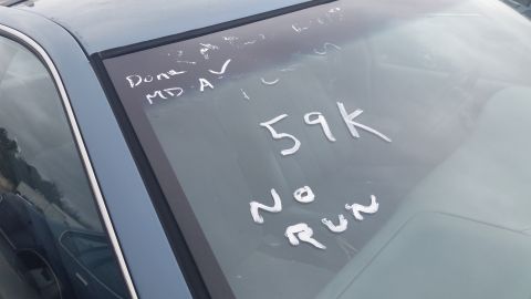 1991 Ford LTD Crown Victoria - Photograph of a car windshield with handwritten salvage-lot markings, not a technical document.
