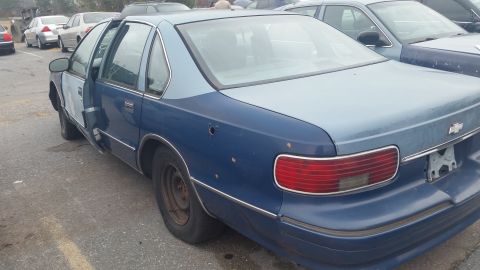 1991 Ford LTD Crown Victoria - Photograph of a blue Chevrolet sedan with an open door, not a technical document.