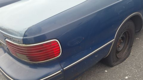 1991 Ford LTD Crown Victoria - Photograph of a blue sedan's rear quarter panel and taillight assembly, not a document.