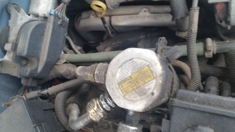 1991 Ford LTD Crown Victoria - Photograph of an engine compartment component with a metal cap and small printed label, not a document.