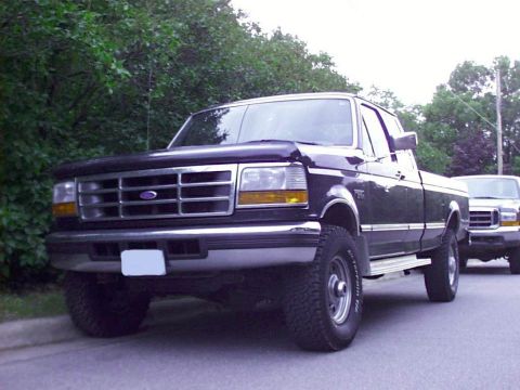 1997 Ford F-250 - A 1997 Ford F-250 truck is parked on the side of the road with another truck behind it.