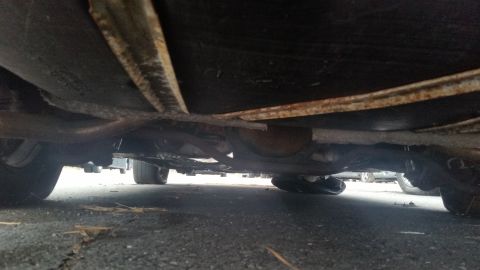 1991 Ford LTD Crown Victoria - Photograph of a vehicle undercarriage with exhaust pipe and rear axle, not a document.