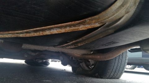1991 Ford LTD Crown Victoria - Photograph of a vehicle undercarriage showing a rusty frame rail and exhaust, not a document.