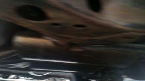 1991 Ford LTD Crown Victoria - Blurry photograph of a vehicle undercarriage and crossmember, not a document.