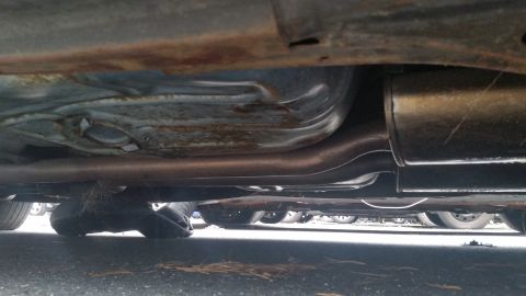 1991 Ford LTD Crown Victoria - Photograph of an exhaust pipe and muffler routed under a vehicle, not a document.