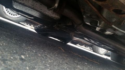 1991 Ford LTD Crown Victoria - Photograph of a vehicle undercarriage and rocker panel with exhaust, not a document.