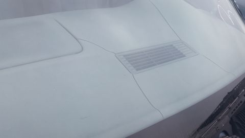 1991 Ford LTD Crown Victoria - Photograph of a vehicle cowl panel and wiper vent grille, not a document.