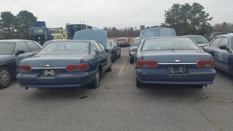1991 Ford LTD Crown Victoria - Photograph of two blue mid-1990s Chevrolet Caprice sedans parked rear-to-camera in an outdoor lot, not a document.