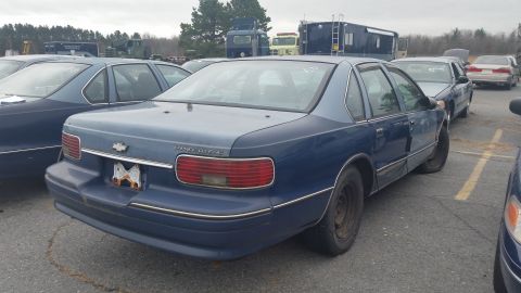 1991 Ford LTD Crown Victoria - Photograph of a weathered blue Chevrolet Caprice sedan, rear three-quarter view in an outdoor lot, not a document.