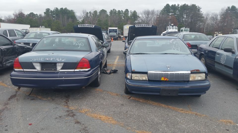 dark Ford Crown Victoria and a Chevrolet Caprice parked nose-out in a lot