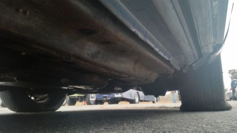 1991 Ford LTD Crown Victoria - Low-angle photograph of a car's underbody and rocker panel area, not a document.
