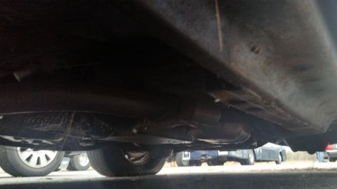 1991 Ford LTD Crown Victoria - Low-angle photograph of a vehicle undercarriage showing the floor pan and exhaust, not a document.