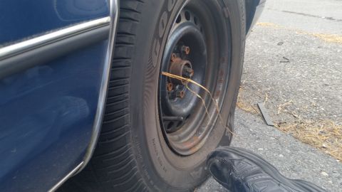 1991 Ford LTD Crown Victoria - Photograph of a steel wheel and tire on a blue car, not a document.