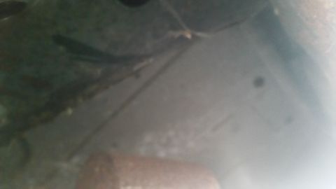 1991 Ford LTD Crown Victoria - Dark, blurry photograph of an exhaust component under a vehicle, not a document.