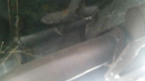 1991 Ford LTD Crown Victoria - Blurry low-light photograph of an exhaust pipe and undercarriage, not a document.