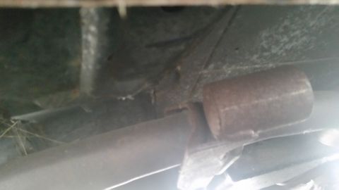 1991 Ford LTD Crown Victoria - Close-up photograph of a rusty muffler and frame area under a vehicle, not a document.