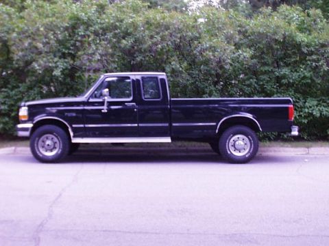 1997 Ford F-250 - Side profile of a black 1997 Ford F-250 pickup truck parked on a street.
