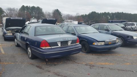 1991 Ford LTD Crown Victoria - Photograph of decommissioned-looking Crown Victoria and Caprice sedans in an outdoor lot, not a document.