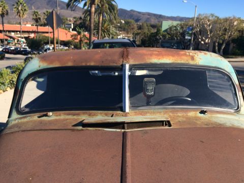 1968 Ford Mustang - Photograph of the rusted rear window and trunk of a patina vintage car parked on a street.