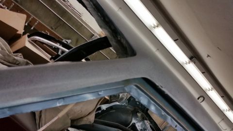 2001 Ford Crown Victoria - Photograph of a vehicle A-pillar and roof rail in a body shop, not a technical document.