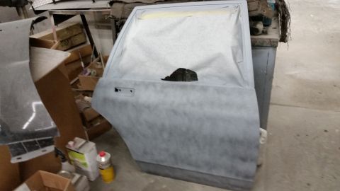 2001 Ford Crown Victoria - Photograph of a primed car door in a restoration shop, not a technical document.