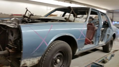 2001 Ford Crown Victoria - Photograph of a partially restored two-door car body on a rack, not a technical document.