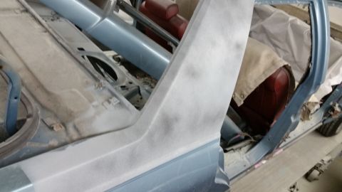 2001 Ford Crown Victoria - Restoration photo of a sedan body shell with primered pillar, not a document.